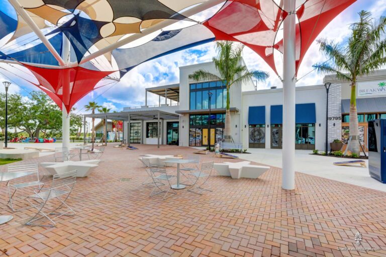 Shaded plaza with colorful sails and café tables in Downtown Wellen, Wellen Park