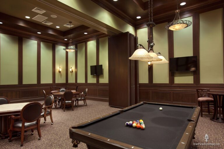 Billiards table and card tables in a wood-paneled game room at the Gran Paradiso clubhouse