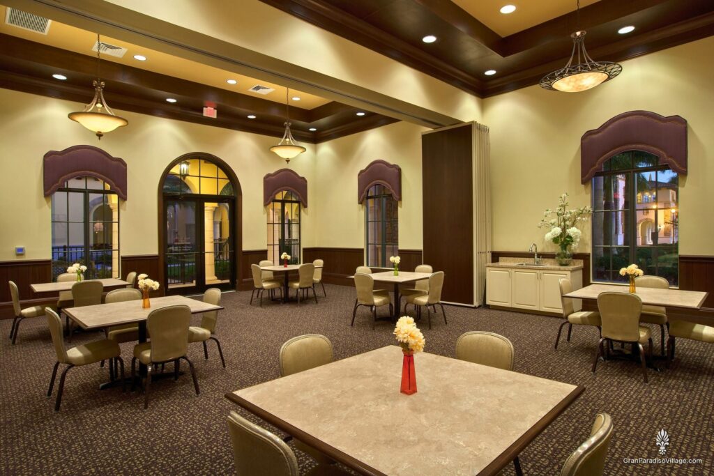 Card room with café-style tables and arched windows at the Gran Paradiso clubhouse in Wellen Park