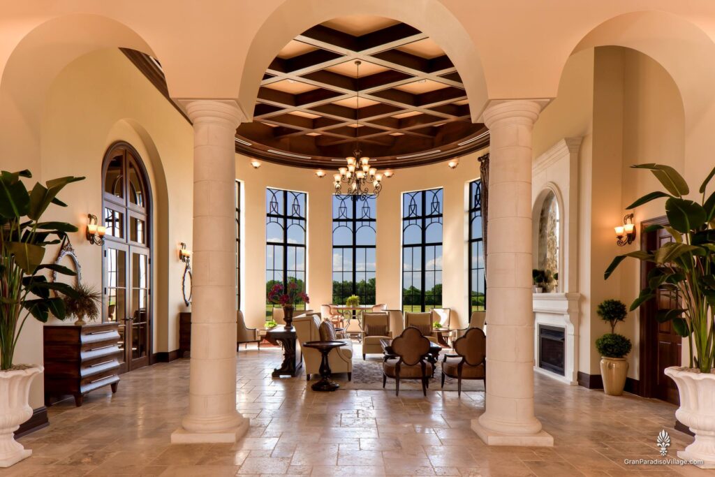 Clubhouse gathering room with a coffered ceiling, chandelier, stone columns and tall arched windows