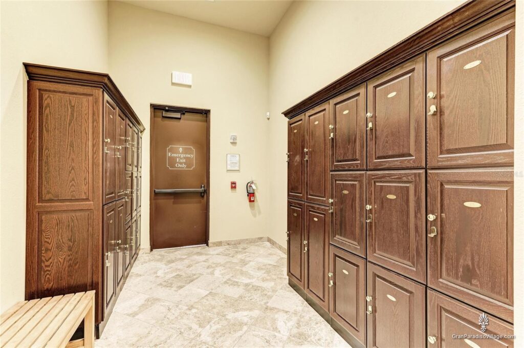 Locker room with rows of wood lockers, a bench and stone floor at the Gran Paradiso clubhouse