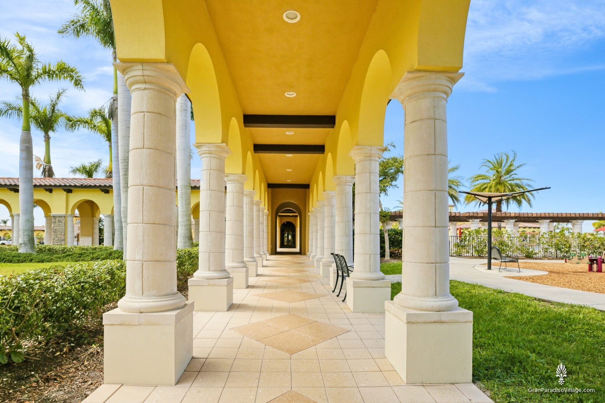 Columned loggia with a tiled walkway and arches beside the clubhouse lawn