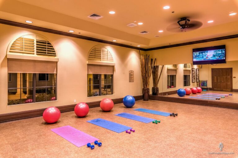 Aerobics studio with a mirrored wall, exercise balls, yoga mats and hand weights