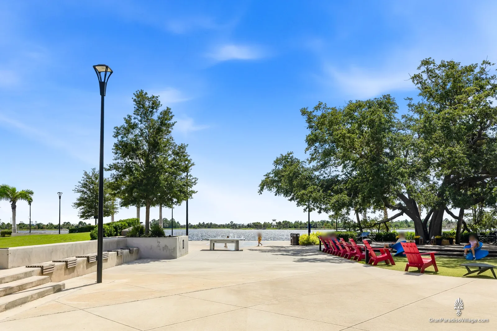 Lakefront plaza in Downtown Wellen with red Adirondack chairs under live oaks beside the Grand Lake