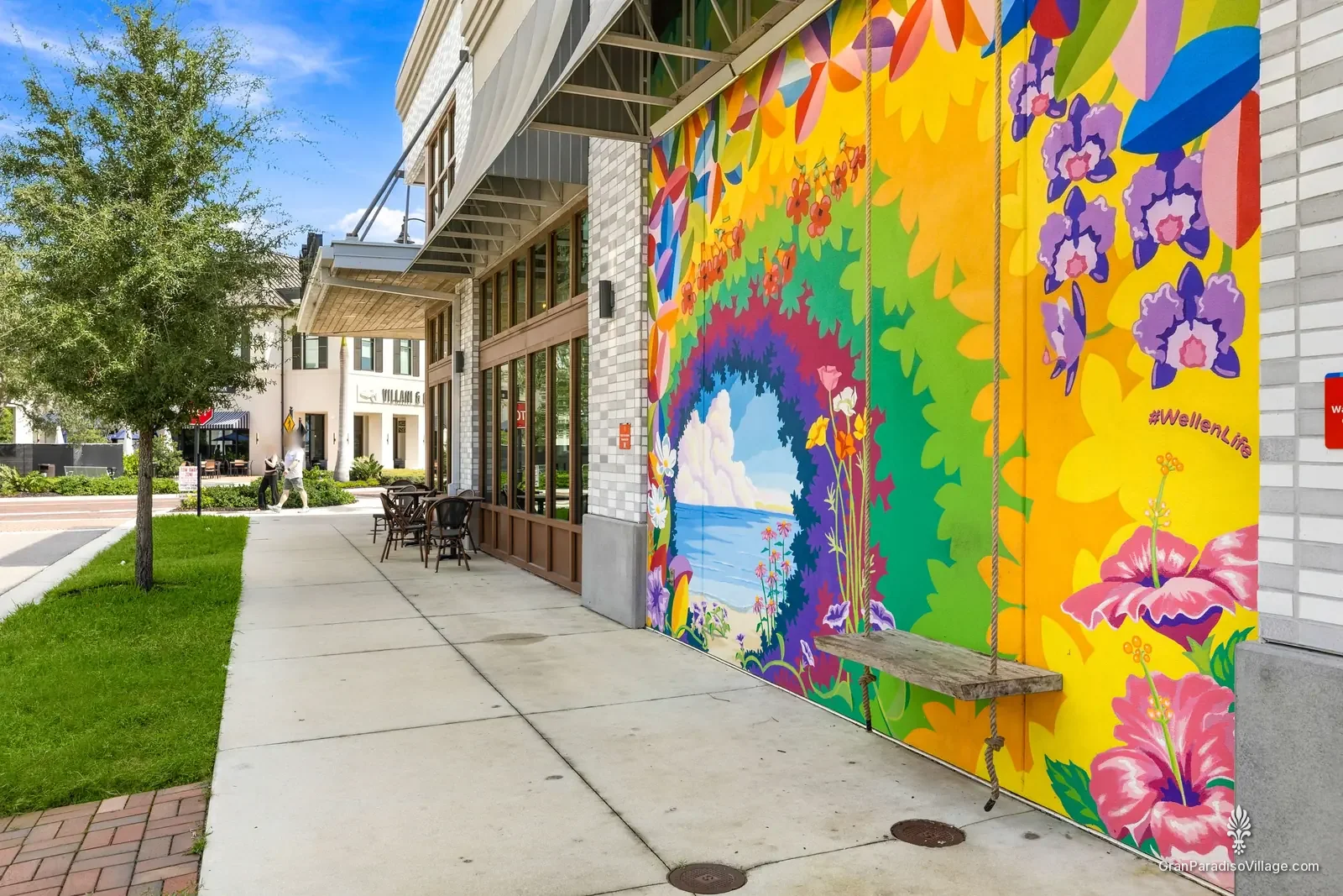 Colorful floral mural with a rope swing on a Downtown Wellen building, tagged #WellenLife