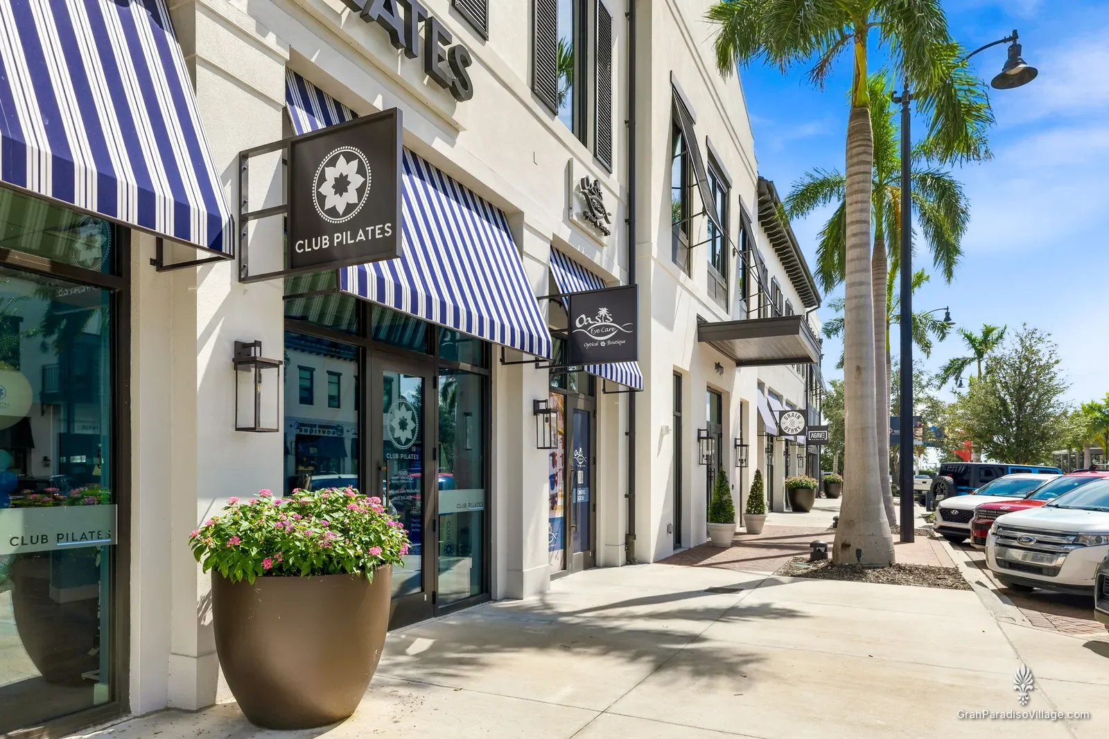 Downtown Wellen sidewalk with navy-and-white striped awnings, a flower planter and palms