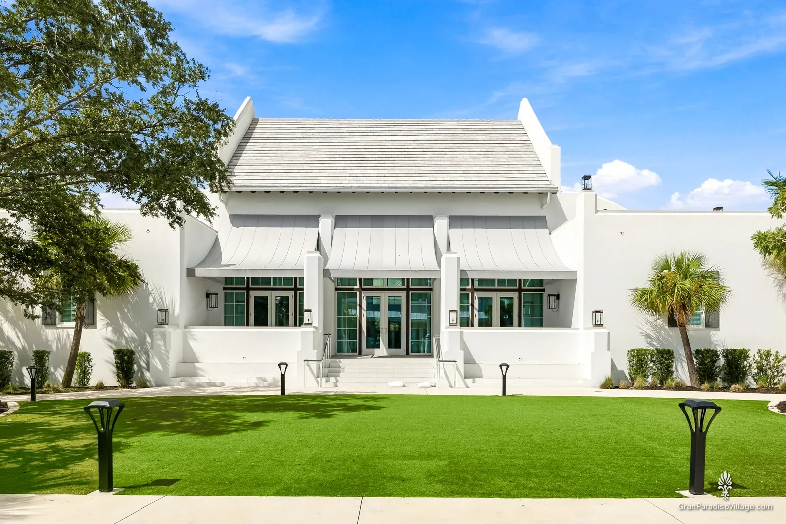 White gabled hall with green doors facing a lawn in Downtown Wellen