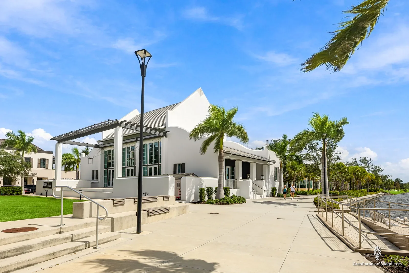 White gabled lakefront building with a trellis, steps and palms in Downtown Wellen
